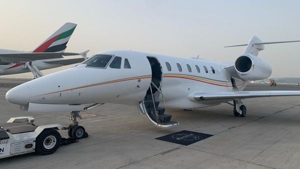 A Cessna Citation X being moved on the runway with its door open. 