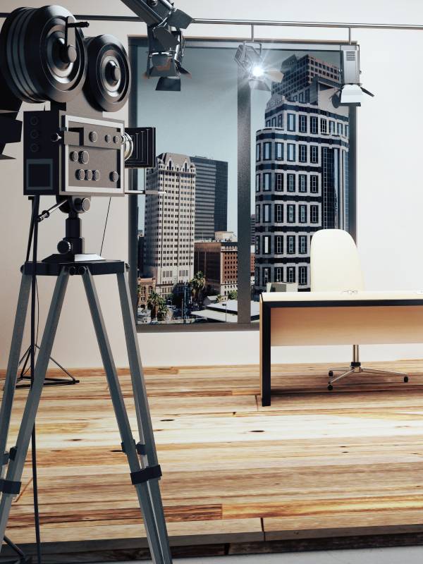 An old-school film camera set up in an office space with a desk 和 pictures of buildings on the wall.