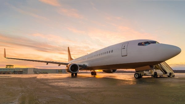 Side view of an airplane taking off with a view of the cityscape in the background.