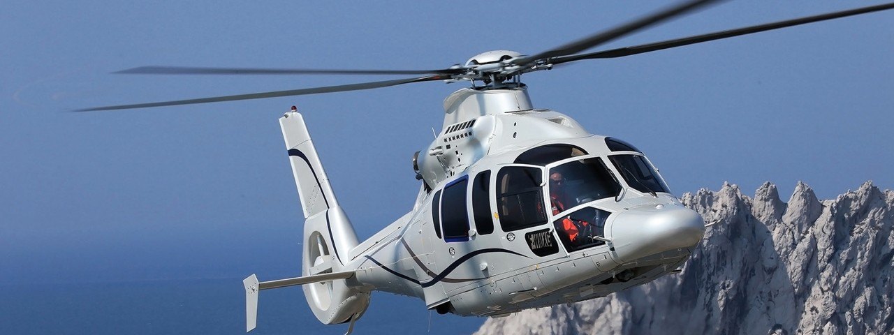 A Eurocopter EC155, now Airbus Helicopters H155, flying through a mountain range.