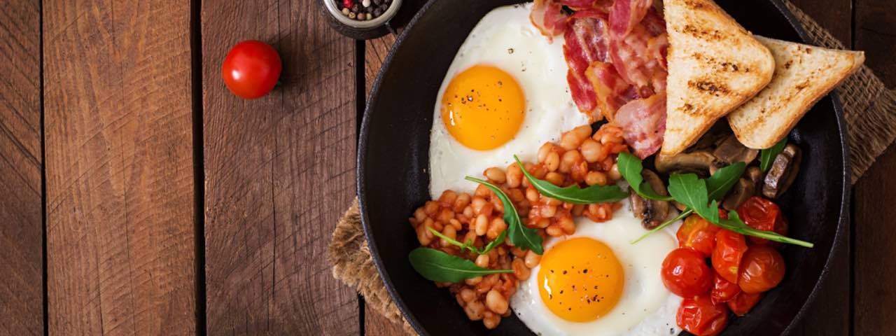 A fry-up breakfast in a pan on a wooden table.