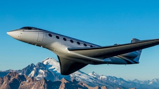 A Gulfstream G650ER flies through a clear sky with snow-capped mountains in the background.