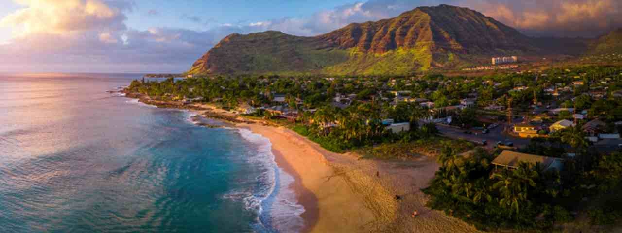 A panoramic view of Papaoneone Beach with houses and mountains in the backdrop.