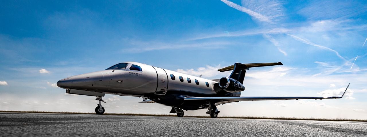 A Phenom 300 jet parked on the runway.