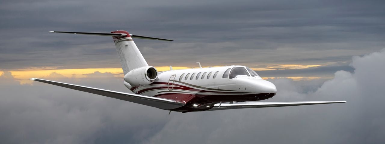 A private jet flying through the clouds at sunset. 