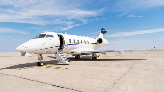 A private jet parked on the tarmac with its stairs down.