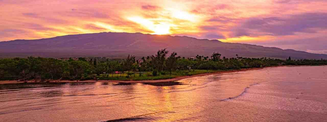  A sunrise and pink skies over the mountain and beach in Maui, Hawaii.