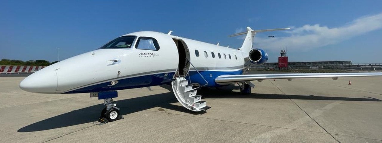 An Embraer Praetor 600 parked on a runway with its stairs down.