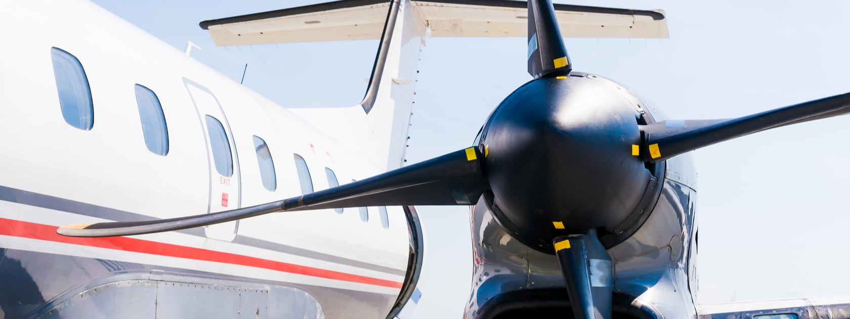  A close up of a private plane propeller and side of the plane.