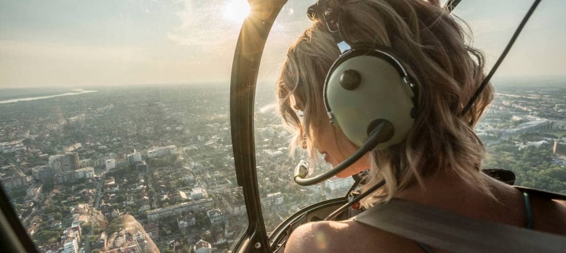 The female pilot in the cockpit looks at the city view 