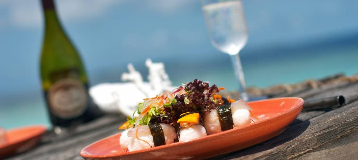 Sushi with salad on a wooden table, with the ocean in the background