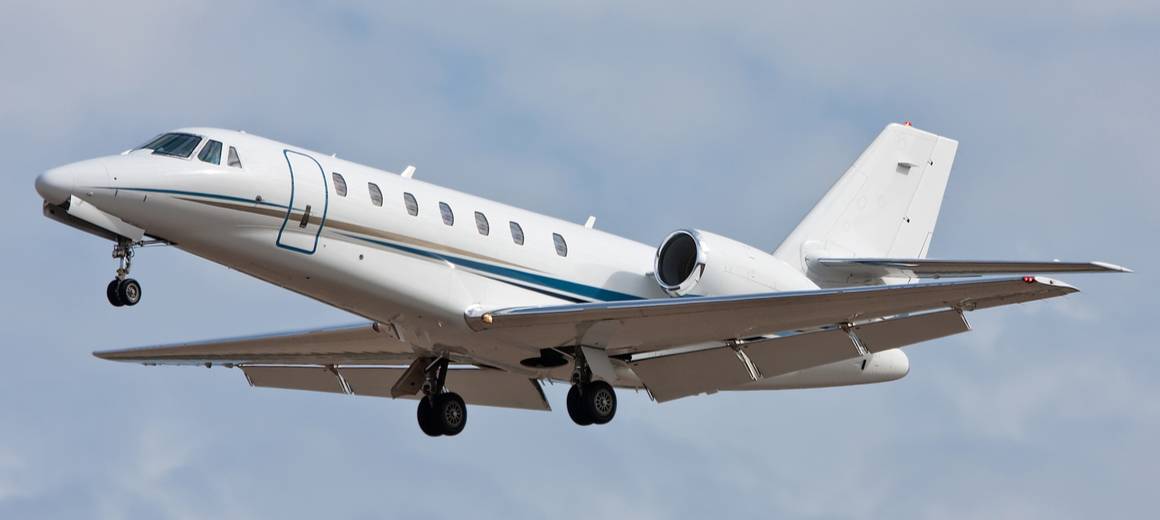 A long shot of a white Cessna Citation Sovereign flying in the sky.