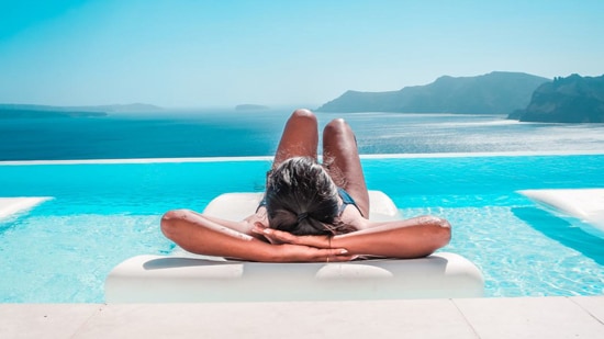 Woman sunbathing on a pool bed with a beautiful view of the sea and mountains.