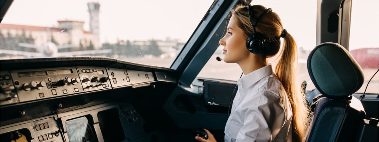 A female trainee pilot in the cockpit of a large commercial airplane.