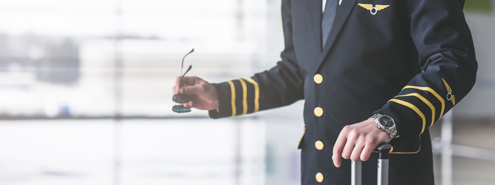 A pilot in uniform standing in an airport waiting room about to board a plane.