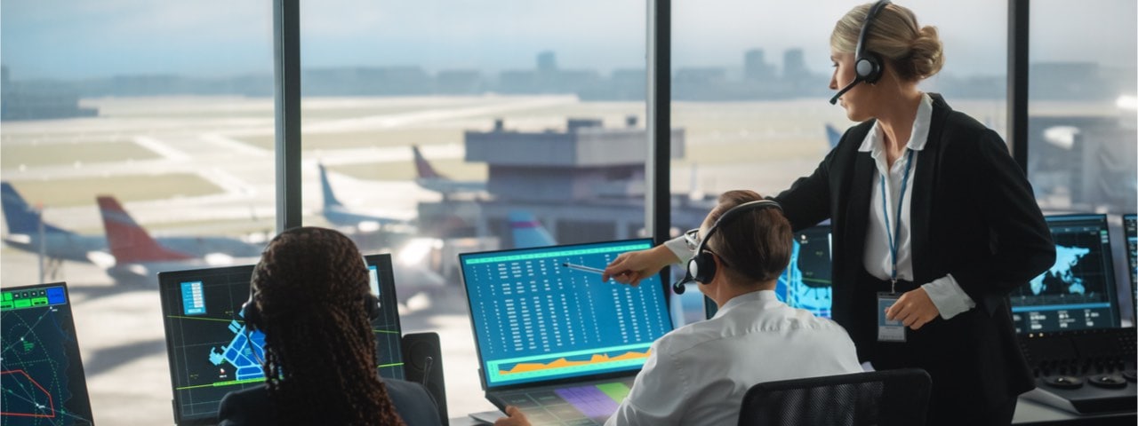 Three air traffic controllers having a conversation in a traffic control tower.