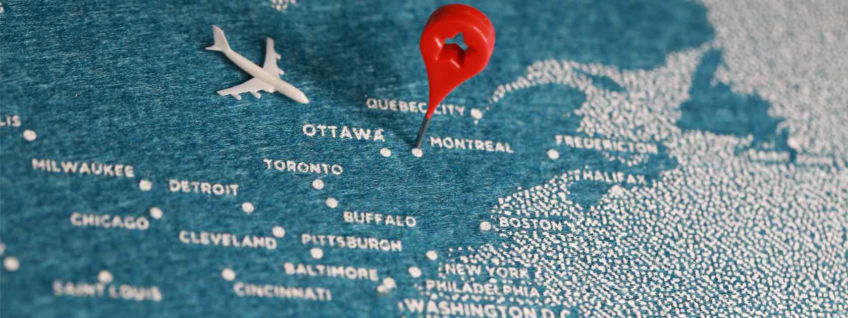 Blue travel map of Canada with a red pin on Montreal.