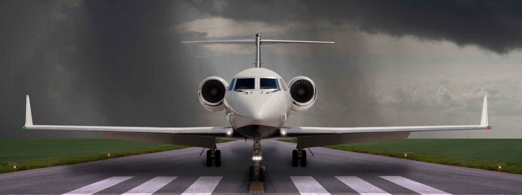 A private jet parked on a runway with storm clouds in the background.