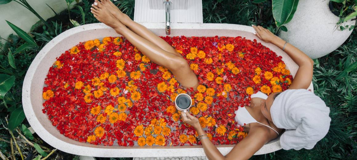 A woman relaxing in a bathtub filled with flower petals.