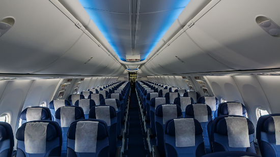 An empty aeroplane with navy blue and white aeroplane seats.