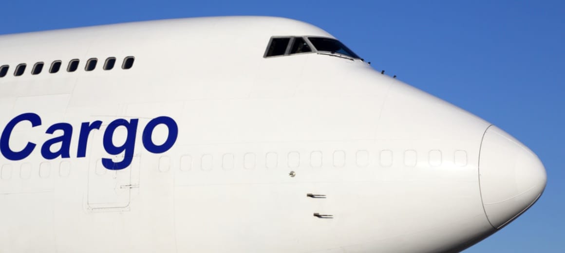Front nose of large white cargo plane with the word cargo written on it in blue