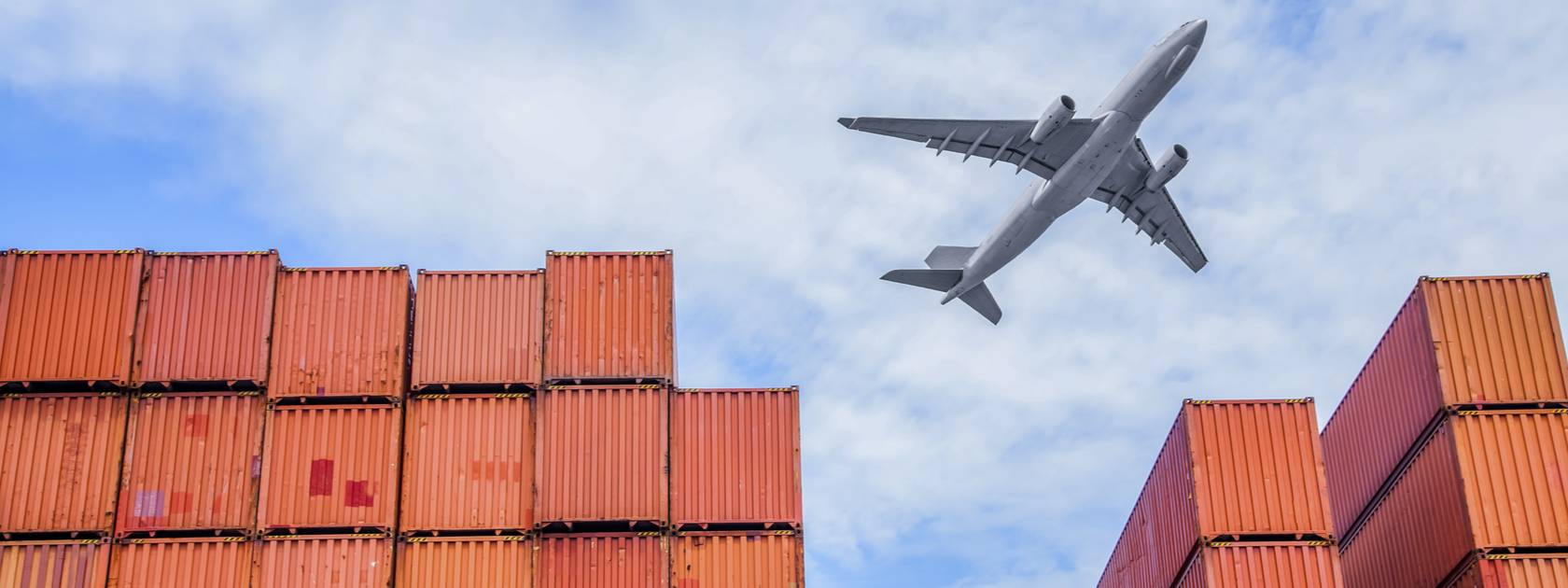 Cargo plane flying over shipping containers 