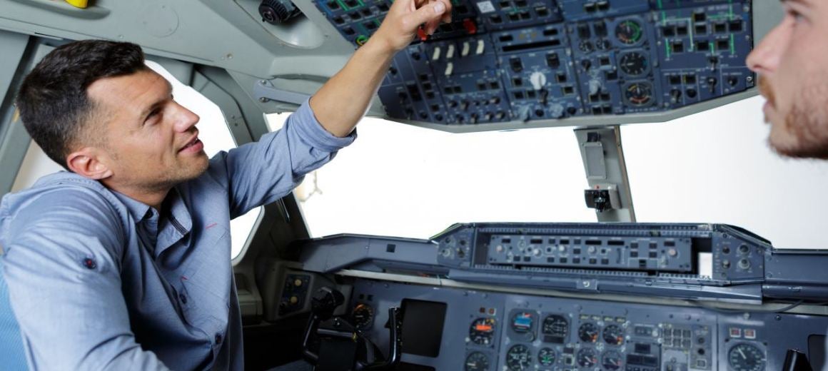 Two men in flight school in modern flight simulator for pilot training