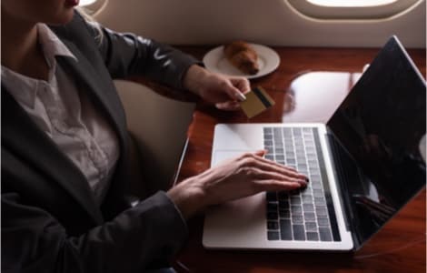 A person on a private plane with their credit card out, buying something on a laptop.