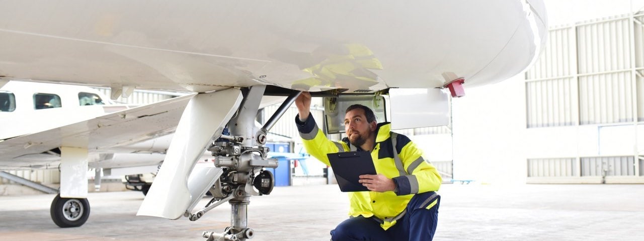 Ground personnel leading a pre-buy inspection and checking the hydraulic system of the landing gear of the aircraft.