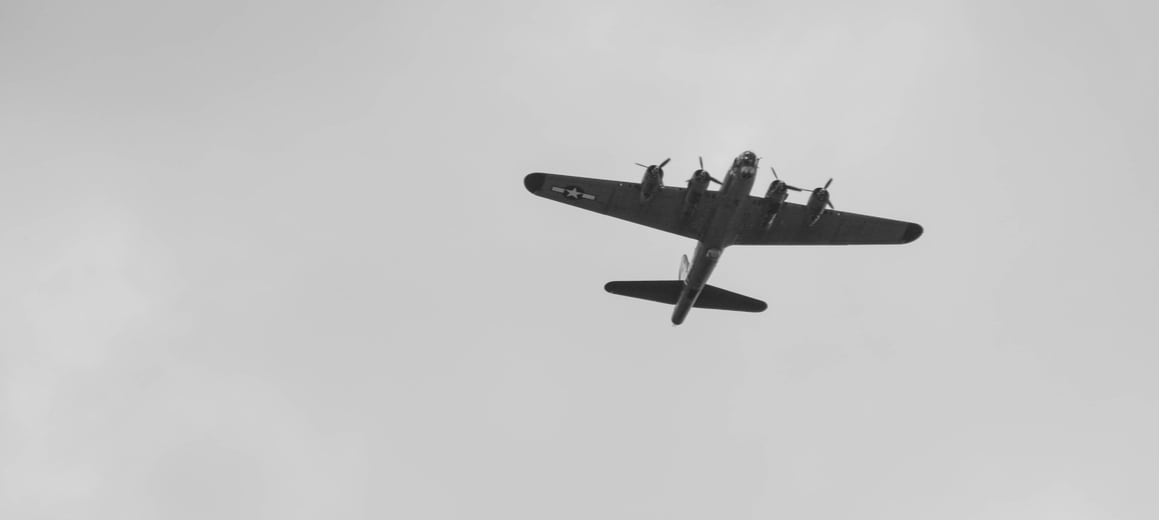 Black-and-white photograph of a Second World War-era bomber flying overhead during a demonstration at an airshow.