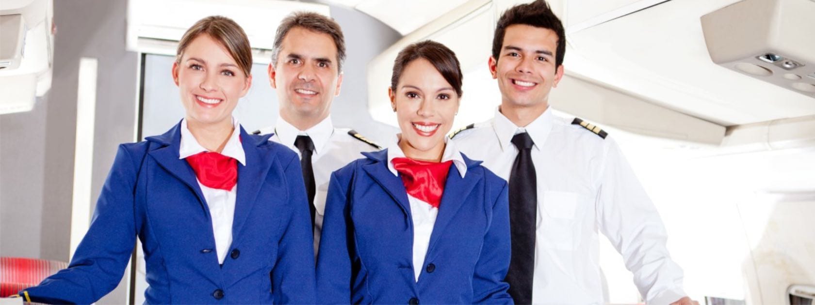 A group of flight attendants smiling to welcome passengers on board.  