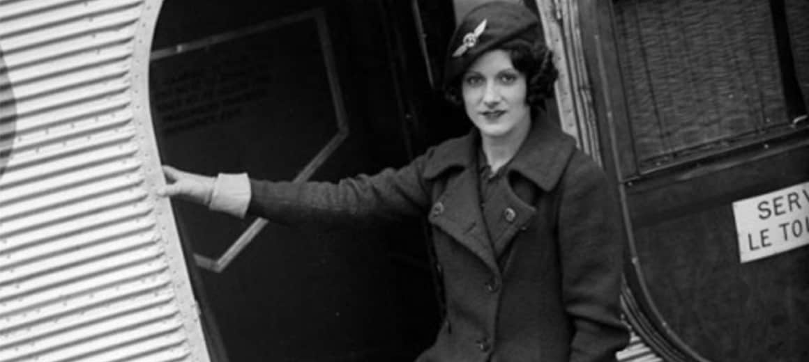 Black and white image of Ellen Church in her cabin uniform standing in an aeroplane entrance.