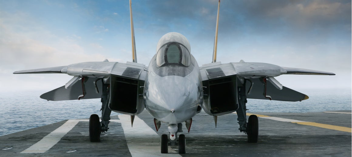 An F-14 fighter jet on the deck of an aircraft carrier.