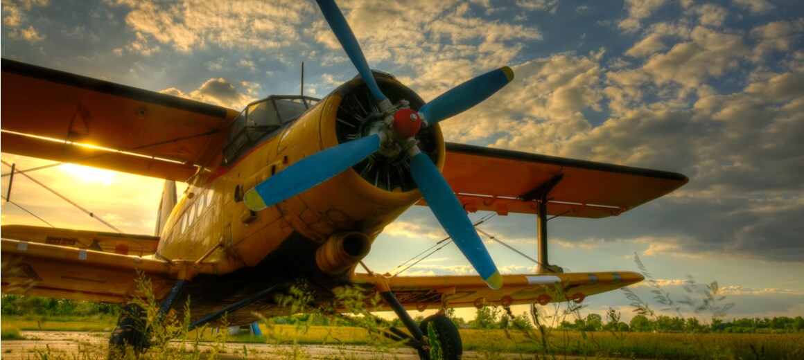 An old aircraft in a field as the sun sets.