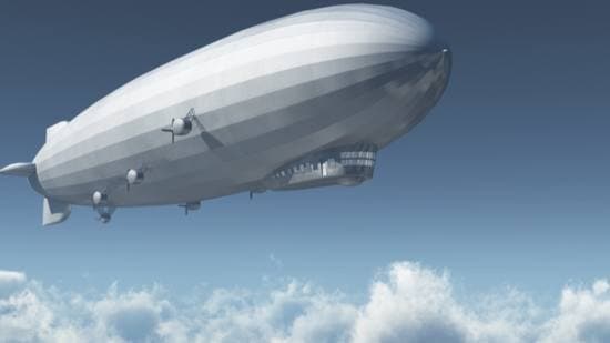 A modern airship flies above the clouds against a blue sky