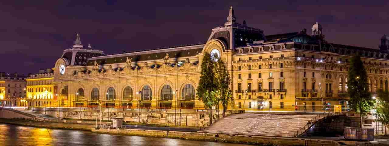 Musée Orsay lit up at night as seen from the river.
