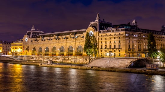 Musée Orsay lit up at night as seen from the river.