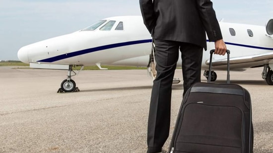 man with suitcase in front of private jet