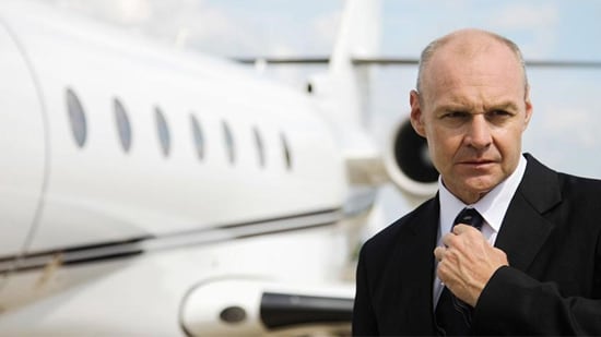A Business man stands next to a private jet