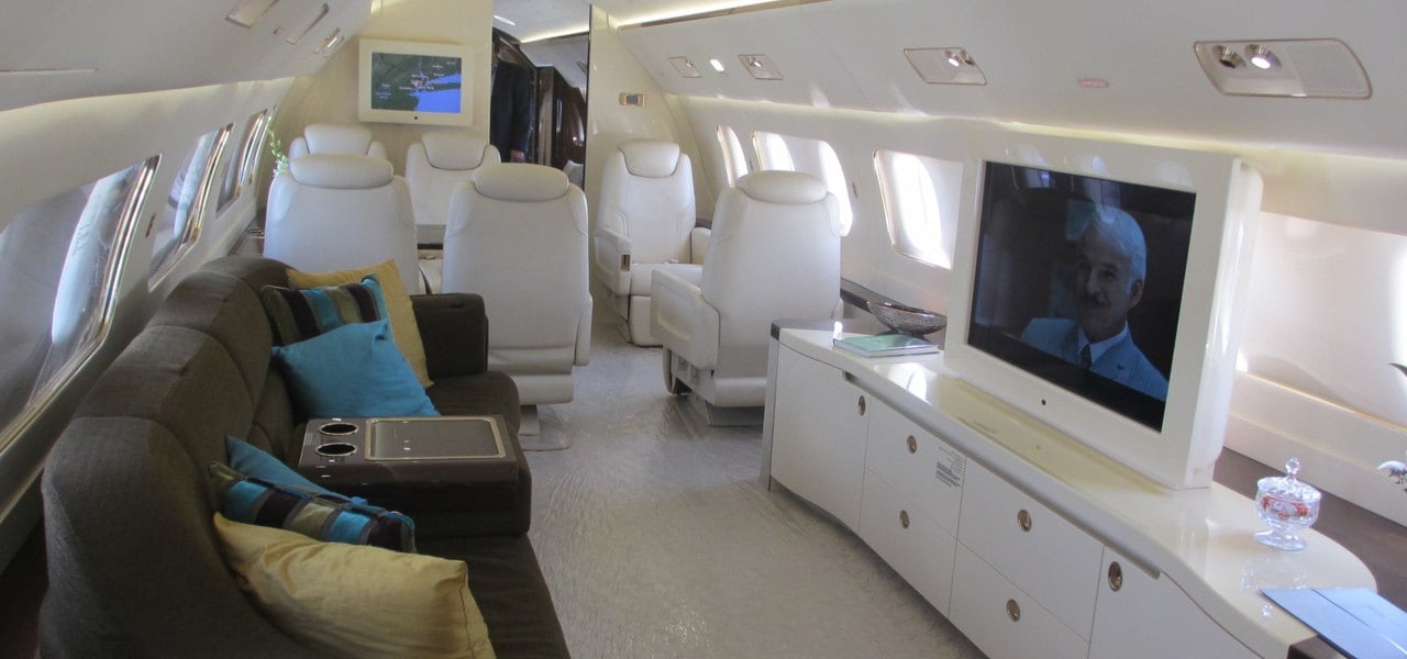 Embraer Lineage 1000E interior with white leather seats and brown sofa