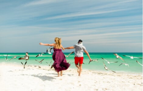 A couple on Miami beach with birds in flight