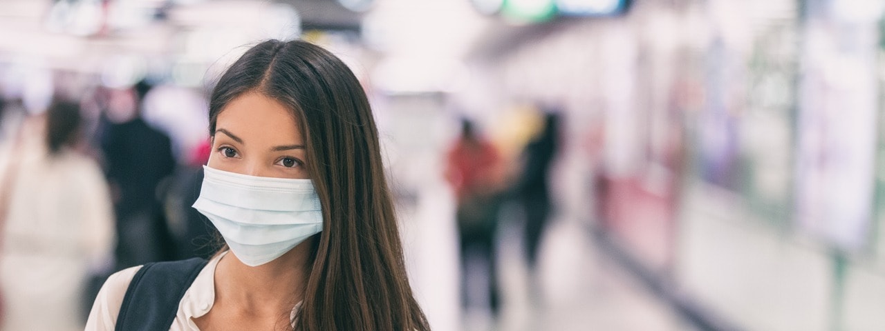 Asian woman wearing flu mask walking on work commute in public space