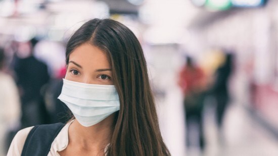 Asian woman wearing flu mask walking on work commute in public space
