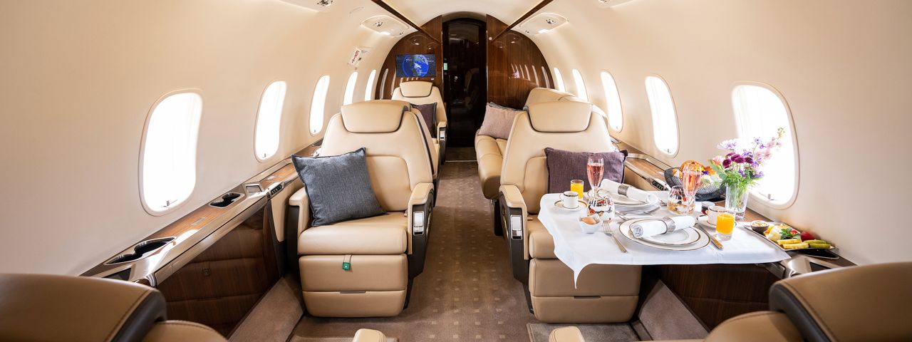 The interior of a private jet, with lunch set up on a fold-down table 