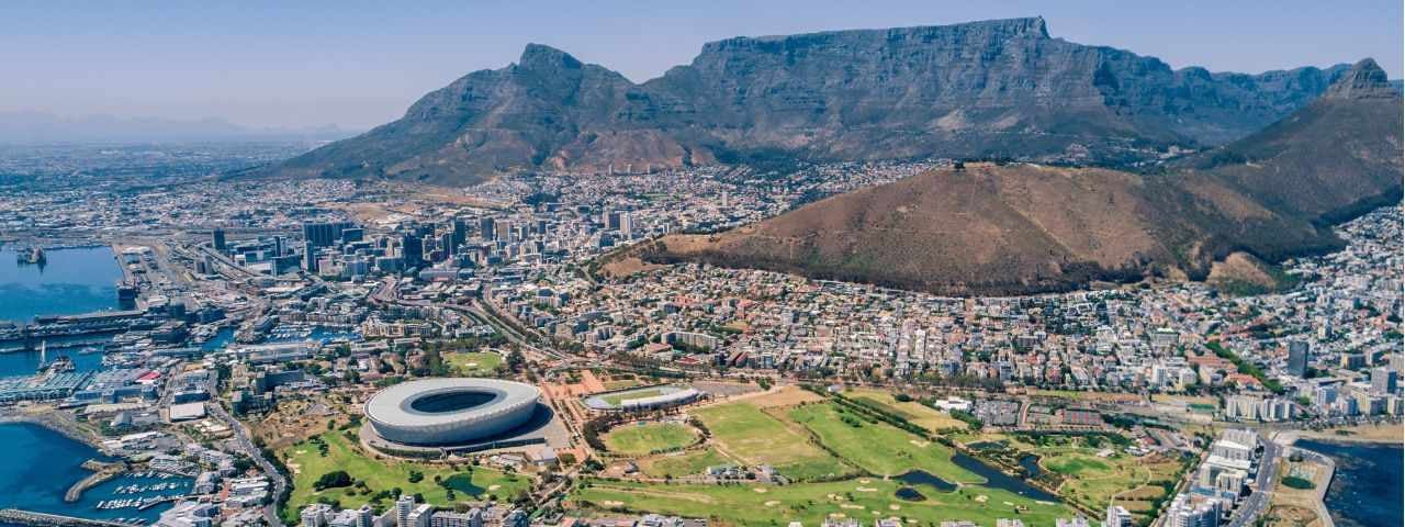 An aerial view of Cape Town, South Africa, showing Table Mountain and the cityscape during sunny weather.