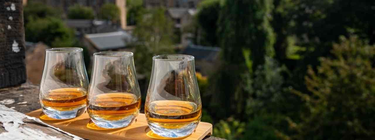 Three whisky-tasting glasses on a balcony. 