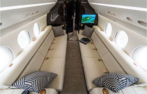 Two long, lavish couches and a flat screen TV inside a private jet