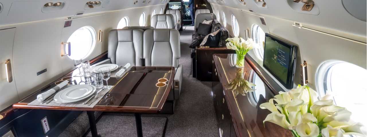 Luxury private jet interior with wooden sideboard and tables.