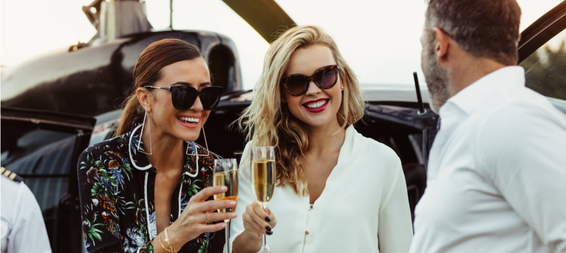 Two women drink champagne after disembarking from a private plane charter