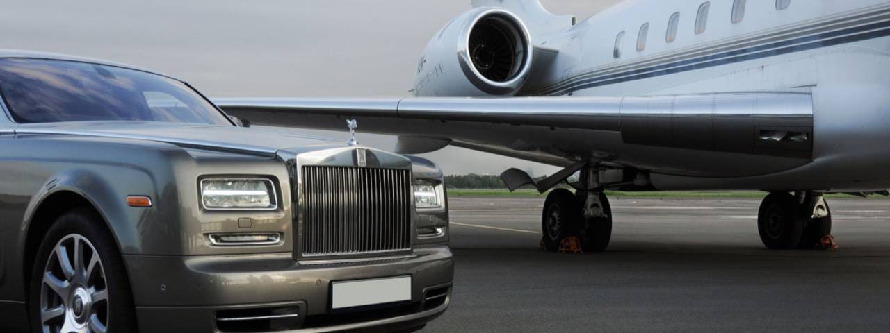 A black luxury car park next to the private jet.